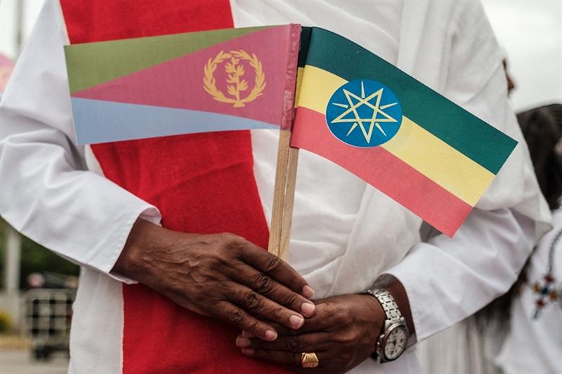 A man holds National flags of Eritrea (L) and Ethiopia as he waits for the arrival of Eritrea s Pres