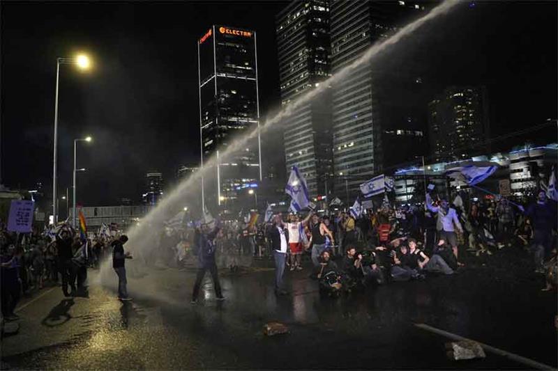 Police deploy a water cannon on Israelis occupying a main highway to protest plans by Prime Minister