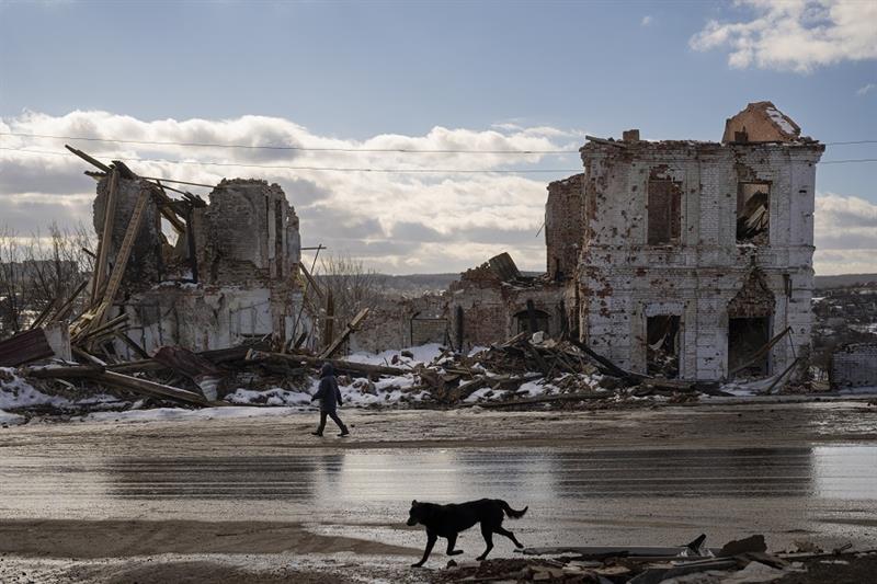 A woman walks by a building destroyed by a Russian strike in Kupiansk, Ukraine, Monday, Feb. 20, 202