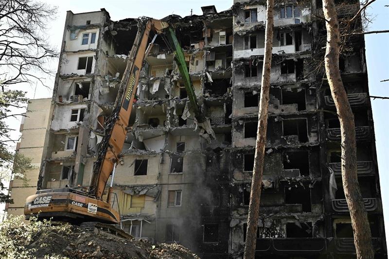 Workers dismantle a heavily damaged residential building in the town of Irpin, on April 21, 2023, am