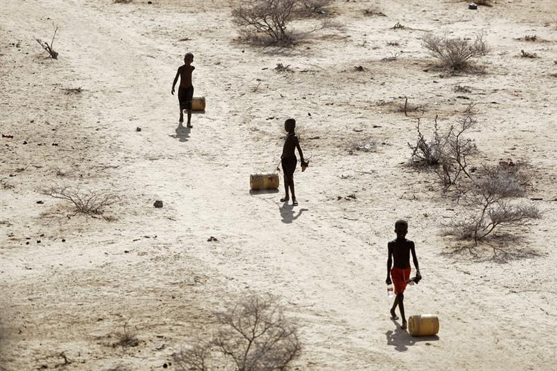  Young boys pull containers of water as they return to their huts from a well in the village of Ntab