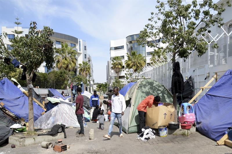 Migrants walk in a makeshift camp outside the International Organization for Migration office, Frida