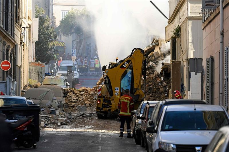 Firefighters stand next to a truck moving rubbles where a building collapsed in Marseille, southern 