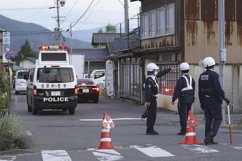Police officers stand guard on a street leading to a building where a man is holed up in Nakano, cen