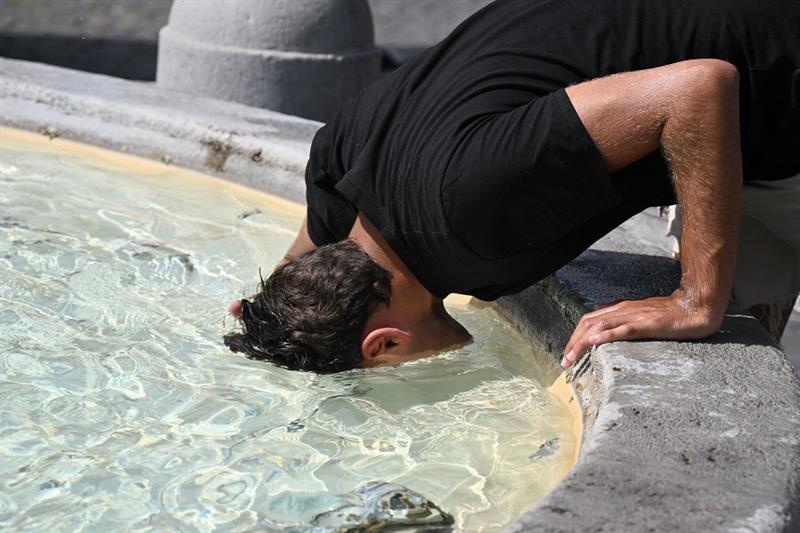 A man puts his head in the water to cool off at the fountain in Piazza del Popolo in Rome, on July 1