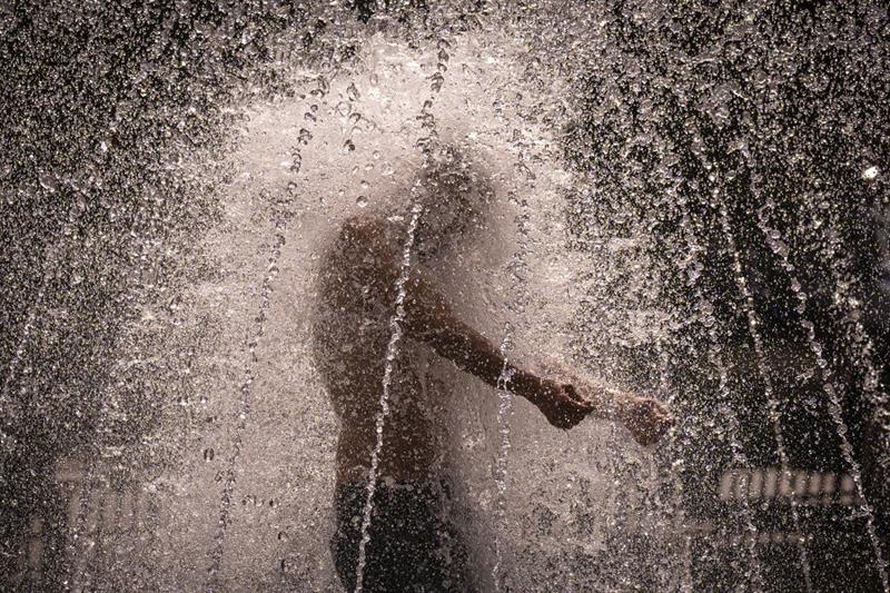 A man stands in a fountain in Bucharest, Romania, on a hot afternoon, July 25, 2023. 