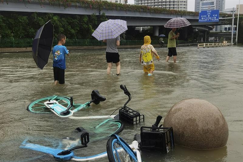 Residents walk through flood waters in the aftermath of Typhoon Doksuri in the city of Fuzhou in sou