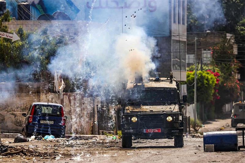 Israeli soldiers fire tear gas canisters from an armoured vehicle during an ongoing military operati