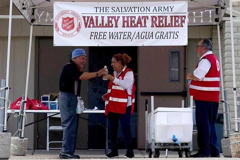 Salvation Army volunteer Francisca Corral, center, gives water to a man at a their Valley Heat Relie