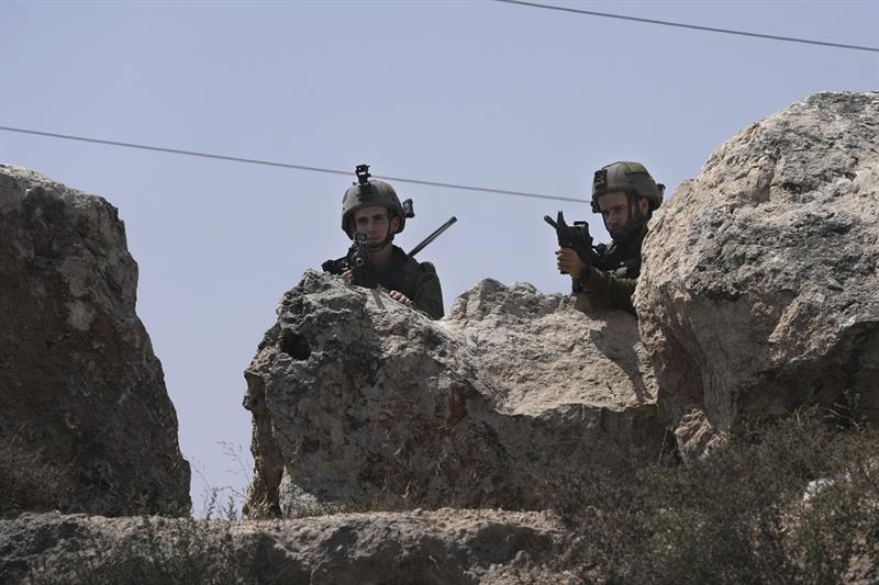 Israeli forces work at the site of a shooting attack near the West Bank city of Hebron, Monday, Aug.