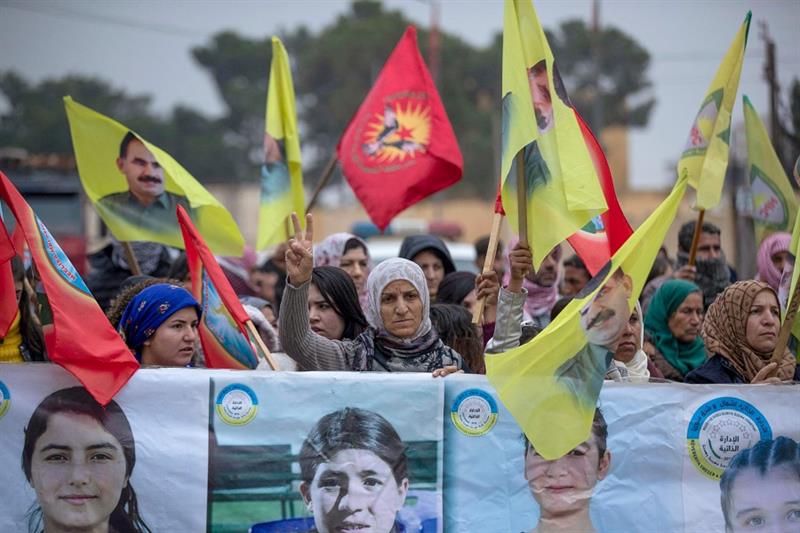 Demonstrators lift banners protesting Turkish strikes and supporting women fighters during a rally o