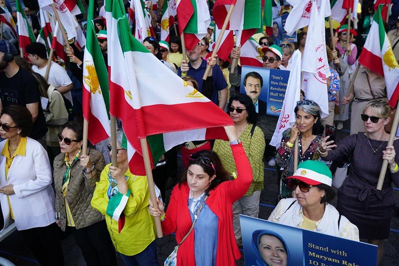 Demonstrators carry flags and signs as members of the Iran opposition protest the planned speech of 