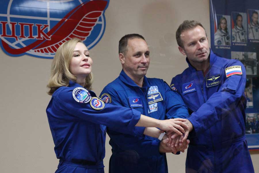This handout photo taken and released on October 4, 2021 by the Russian Space Agency Roscosmos shows crew members, cosmonaut Anton Shkaplerov (C), actress Yulia Peresild (L) and film director Klim Shipenko, shaking hands behind a glass wall during a news conference ahead of the expedition to the International Space Station (ISS) at the Baikonur Cosmodrome, Kazakhstan. AFP 